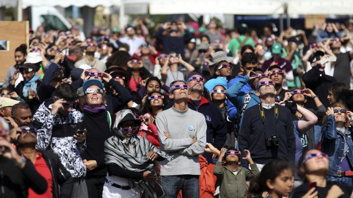 People look through eclipse viewing glasses, telescopes or photo cameras an annular solar eclipse, on September 1, 2016, in Saint-Louis, on the Indian Ocean island of La Reunion. Stargazers in south and central Africa were treated to a spectacular solar eclipse on September 1, 2016 when the Moon wanders into view to make the Sun appear as a "ring of fire", astronomers say. The phenomenon, known as an annular solar eclipse, happens when there is a near-perfect alignment of the Earth, Moon and Sun. But unlike a total eclipse, when the Sun is blacked out, sometimes the Moon is too far from Earth, and its apparent diameter too small, for complete coverage. / AFP PHOTO / Richard BOUHET